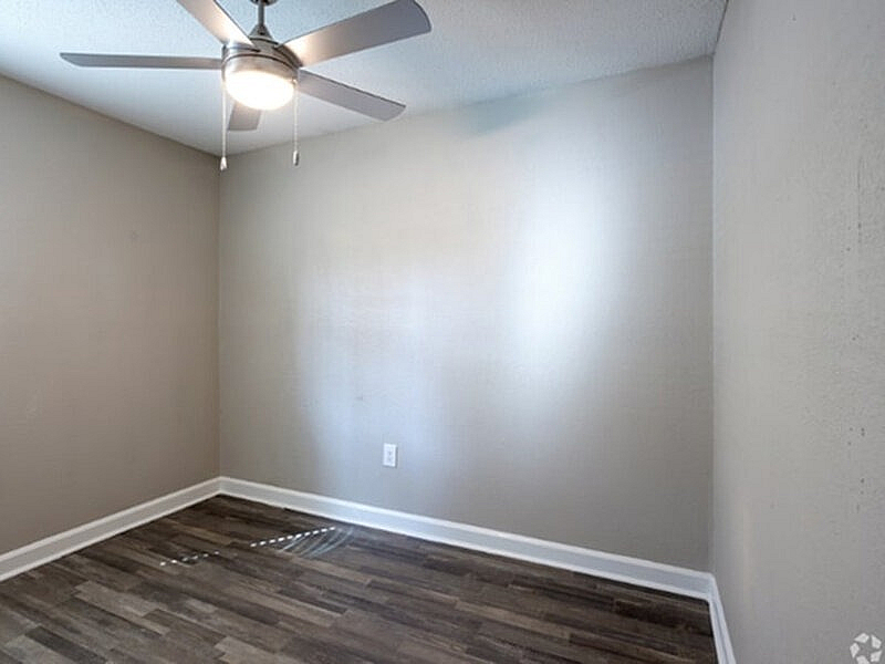 Cozy room with elegant wooden flooring and a modern ceiling fan, perfect for a serene home office or tranquil bedroom.
