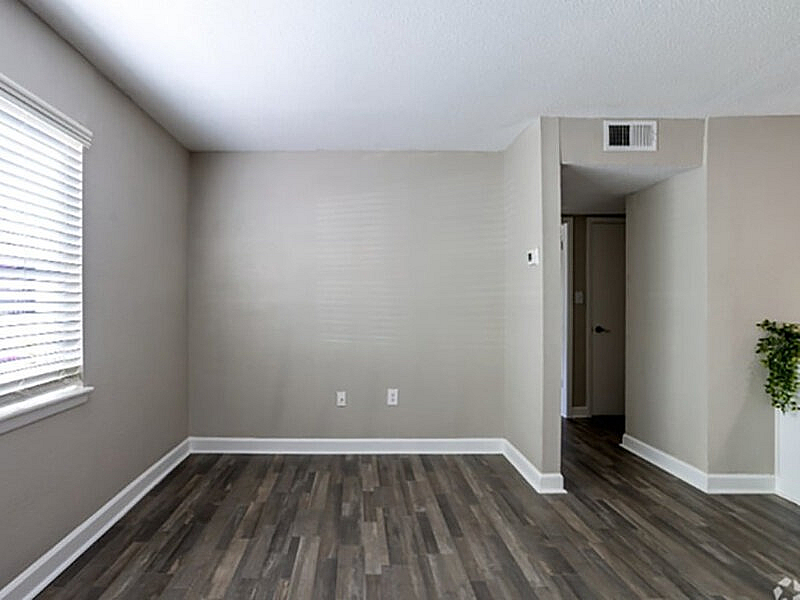 Bright and airy room with modern hardwood flooring and neutral walls, perfect for personalization.
