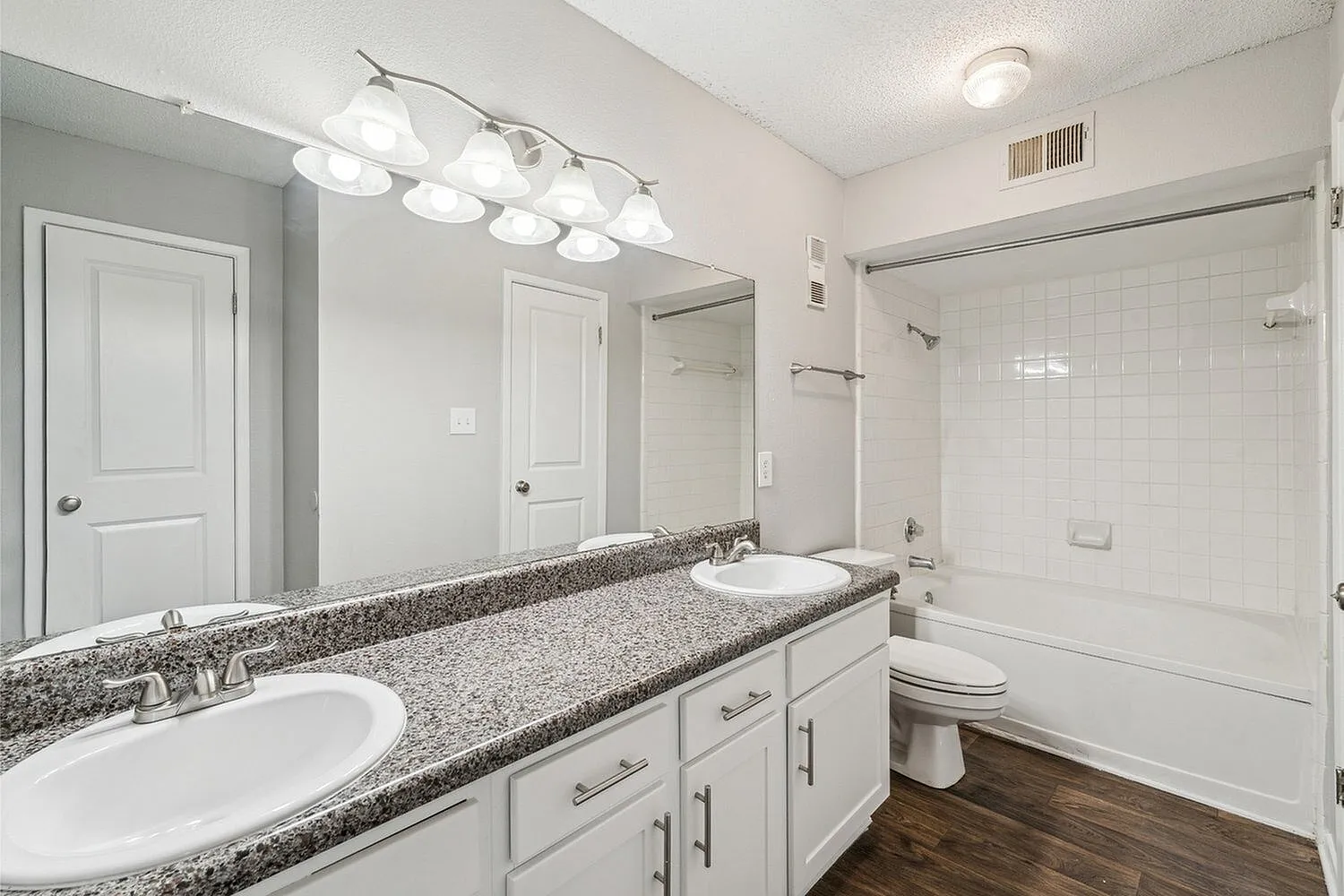 Elegant bathroom with modern double sinks, granite countertop, and bright lighting, offering a luxurious and refreshing space.