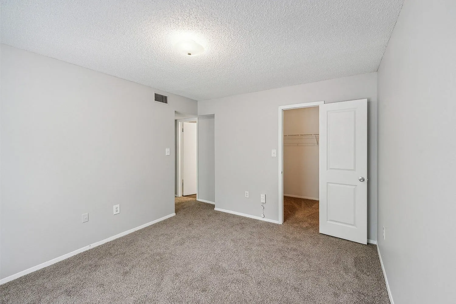 Inviting bedroom with soft carpet flooring, neutral walls, and ample natural light, perfect for personalizing your space.