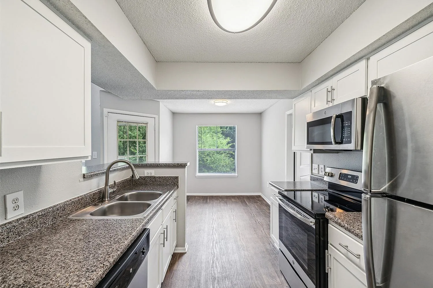 Bright and modern kitchen with stainless steel appliances, sleek granite countertops, and elegant white cabinetry, creating a warm and welcoming space.