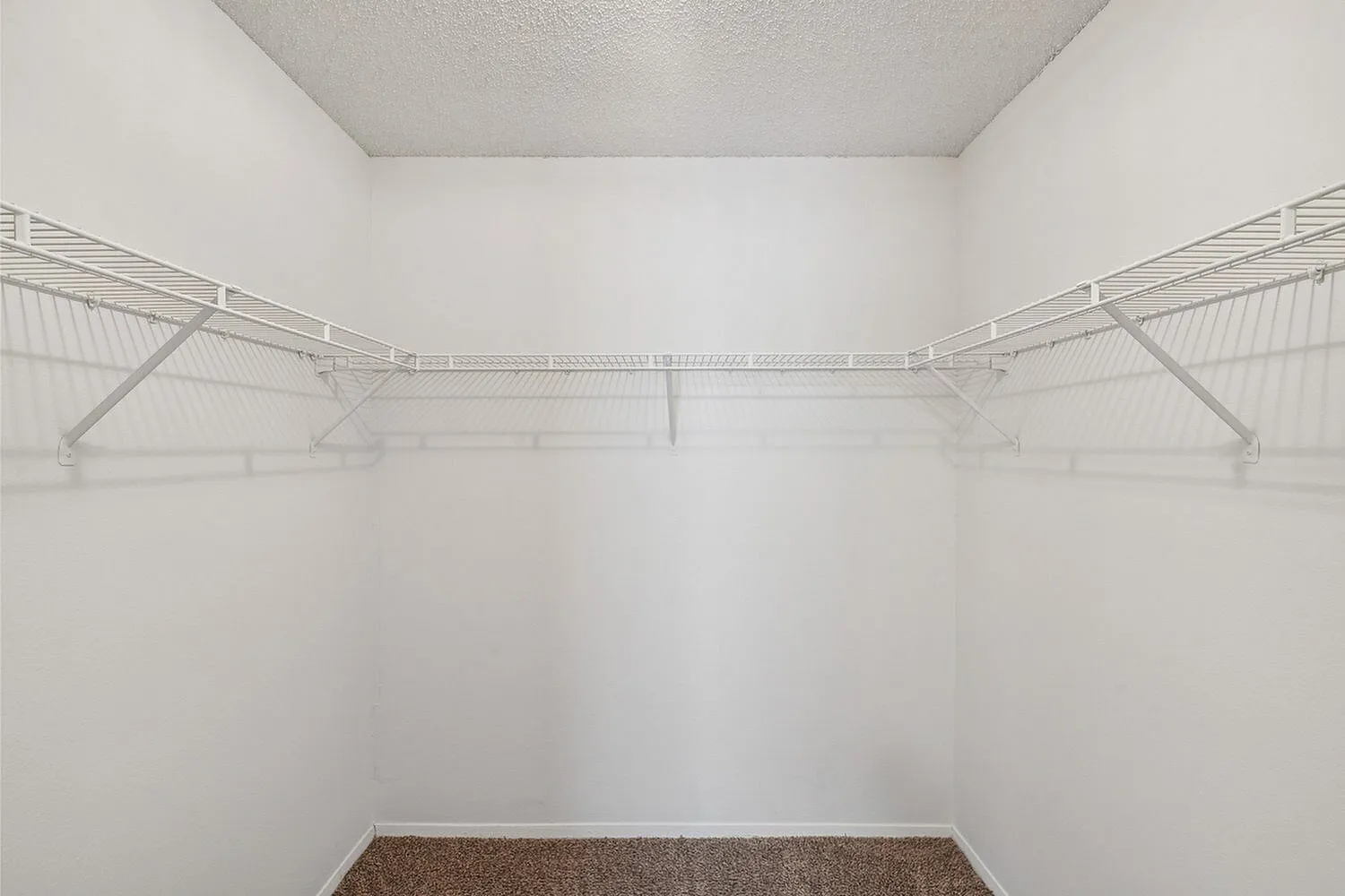 Spacious walk-in closet with sleek white shelving and ample storage space, perfect for organizing your wardrobe.