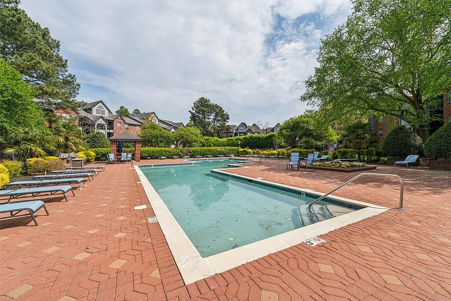 Inviting outdoor swimming pool area surrounded by lush greenery and stylish lounge chairs, perfect for relaxation and social gatherings.