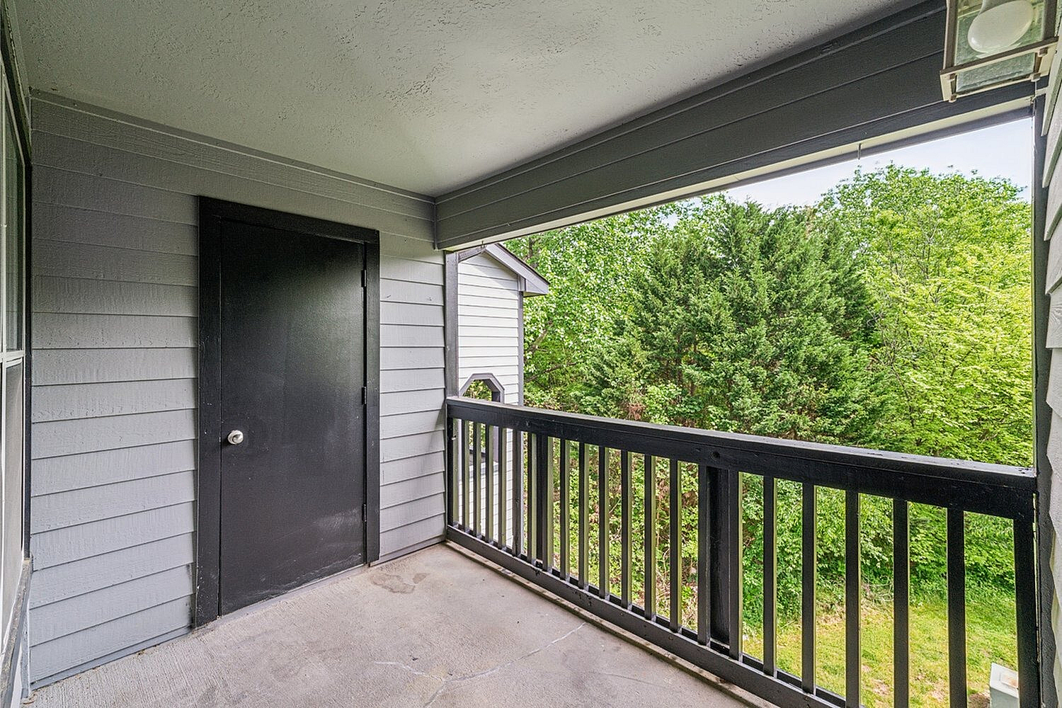 Charming balcony area with sleek railing offering peaceful views of lush greenery.