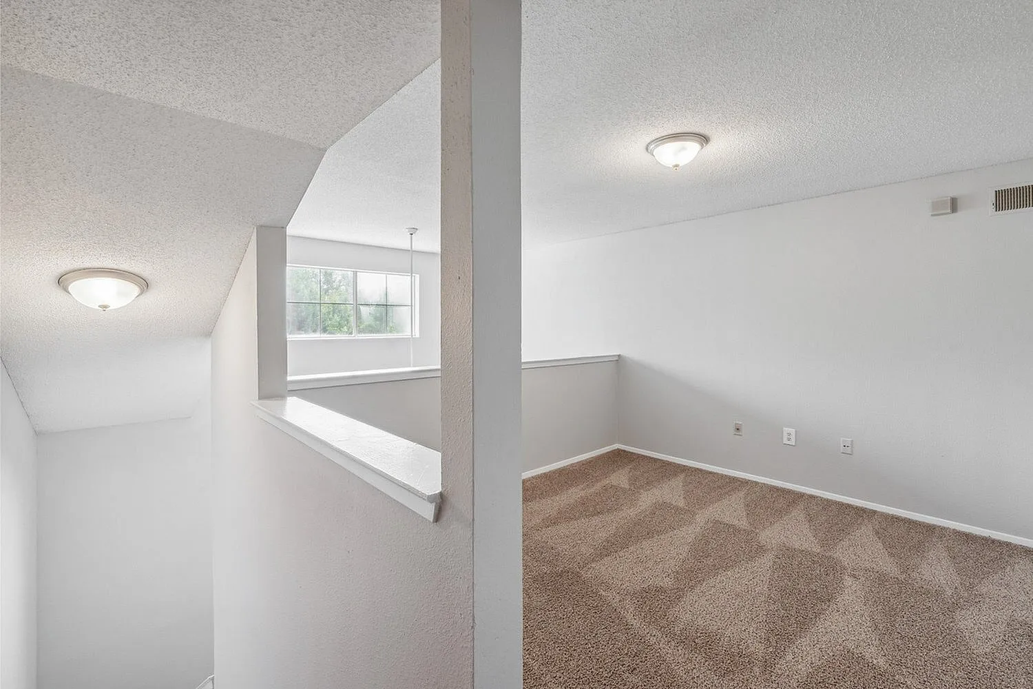Bright and inviting hallway with plush carpet leading to a sunlit open space, offering a seamless and airy layout.