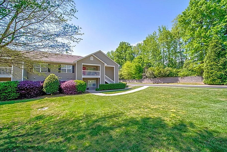Charming apartment complex with manicured lawns and lush greenery, offering serene outdoor living.