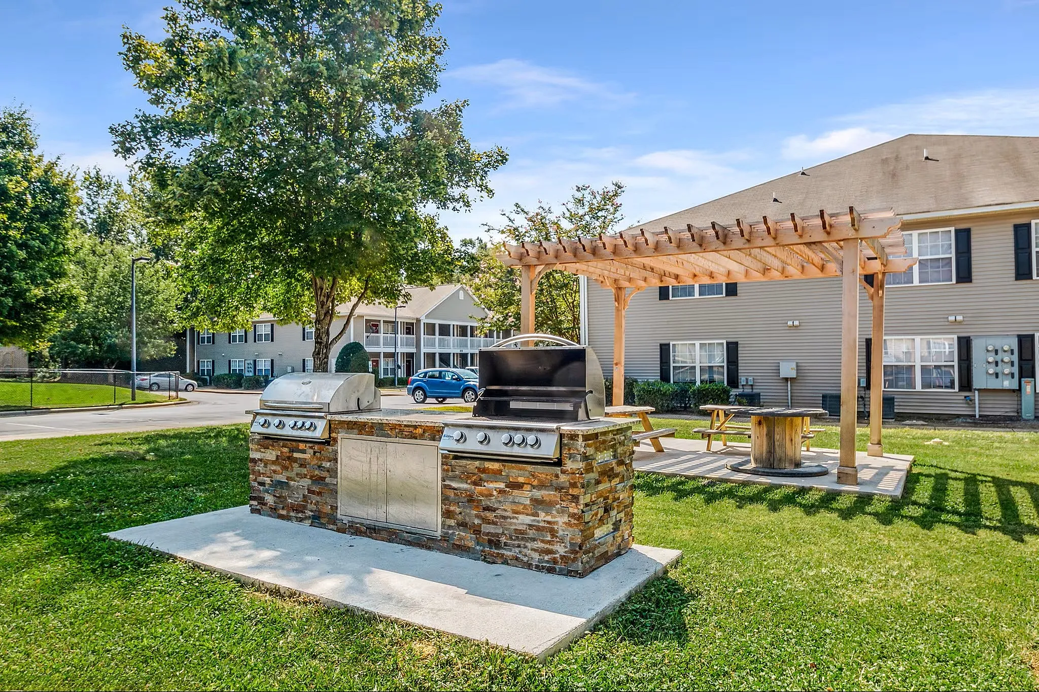 Charming outdoor area featuring a modern stone grill station and inviting pergola with seating, perfect for al fresco gatherings.