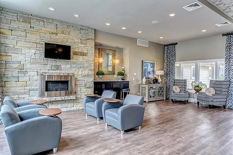 Modern lounge area with elegant stone fireplace, plush seating, and natural light highlighting stylish decor.