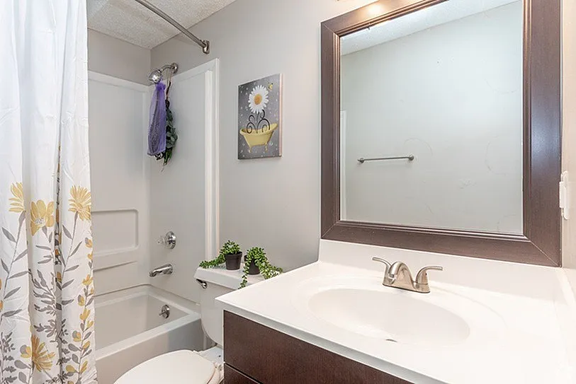 Inviting bathroom with a modern vanity, elegant mirror, and cheerful floral decor, offering a cozy and refreshing space.
