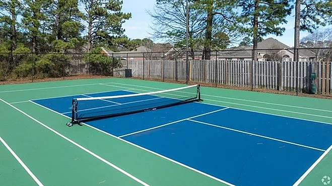 Inviting outdoor tennis court surrounded by lush greenery, perfect for sports enthusiasts.