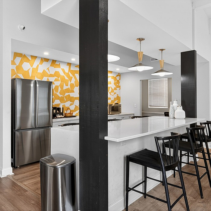 Modern kitchen with sleek bar seating, vibrant yellow geometric backsplash, and stainless steel appliances creating a stylish, inviting atmosphere.