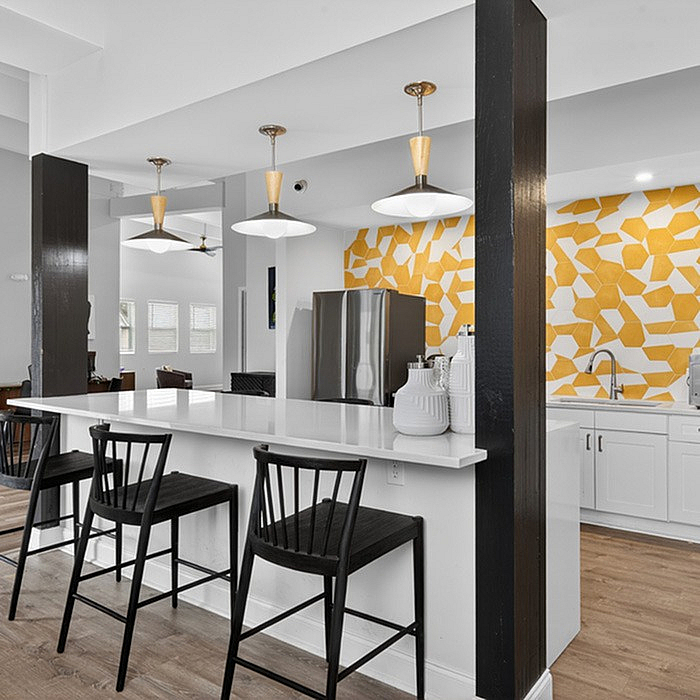 Contemporary kitchen featuring a sleek breakfast bar with chic black chairs, vibrant geometric backsplash, and elegant pendant lighting.