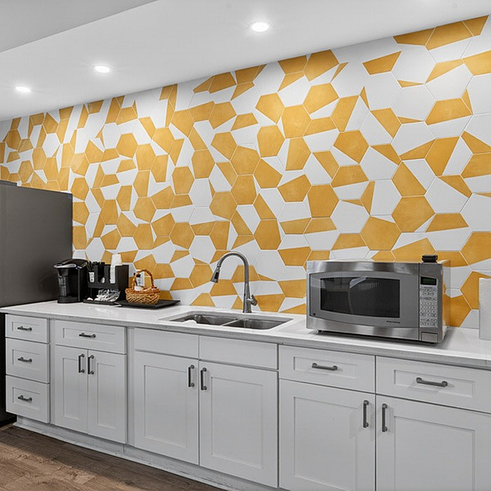 Modern kitchen with geometric yellow and white backsplash, sleek white cabinetry, and stainless steel appliances for a contemporary style.