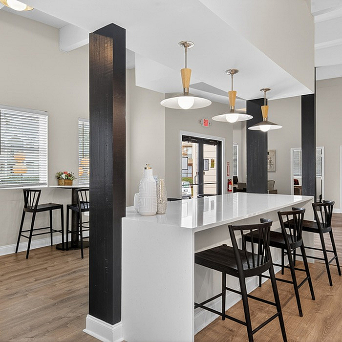 Modern apartment common area with sleek white countertop, elegant pendant lighting, and stylish seating, creating a welcoming atmosphere.