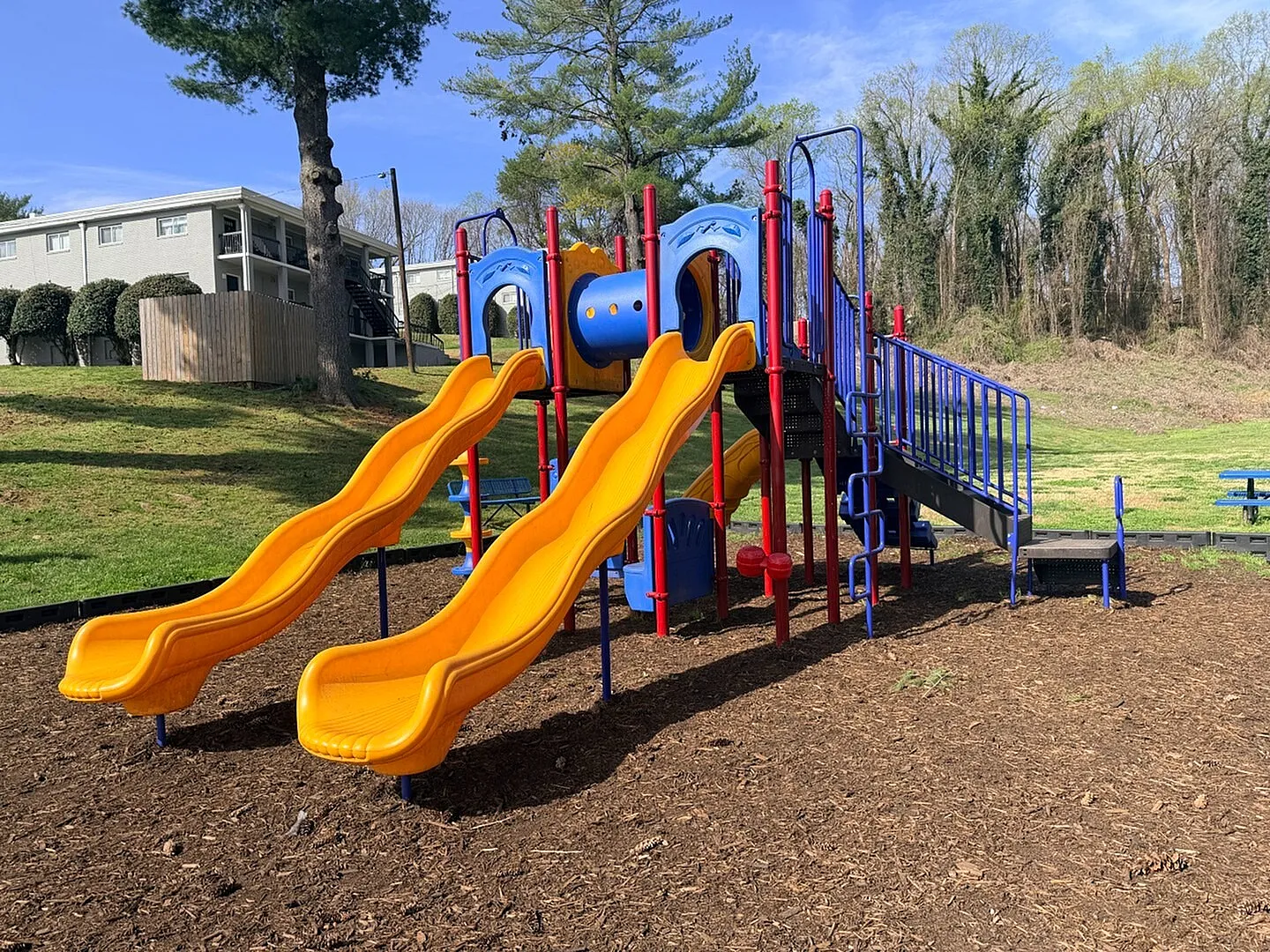 Inviting playground with vibrant slides and climbing structures surrounded by lush greenery, perfect for family fun and outdoor activities.
