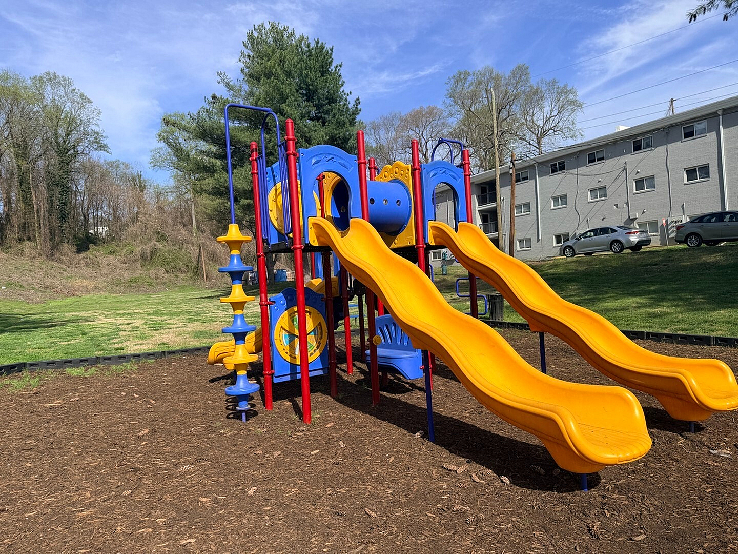 Vibrant playground with colorful slides and climbing structures, set in a lush green outdoor space, perfect for family enjoyment.