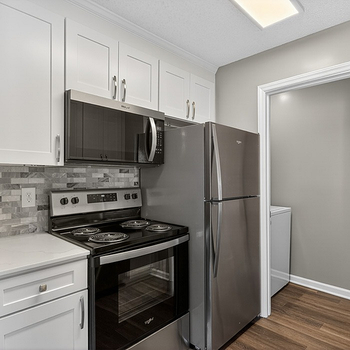 Modern kitchen with sleek stainless steel appliances, pristine white cabinets, and elegant tile backsplash.