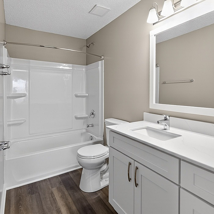 Modern bathroom showcasing sleek white cabinetry, polished countertops, and a gleaming bathtub with shower accents.
