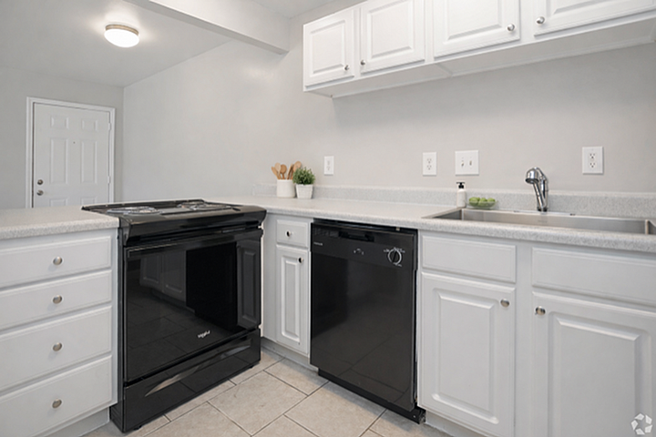 Modern kitchen with sleek black and white cabinetry, featuring new appliances and elegant countertop space.