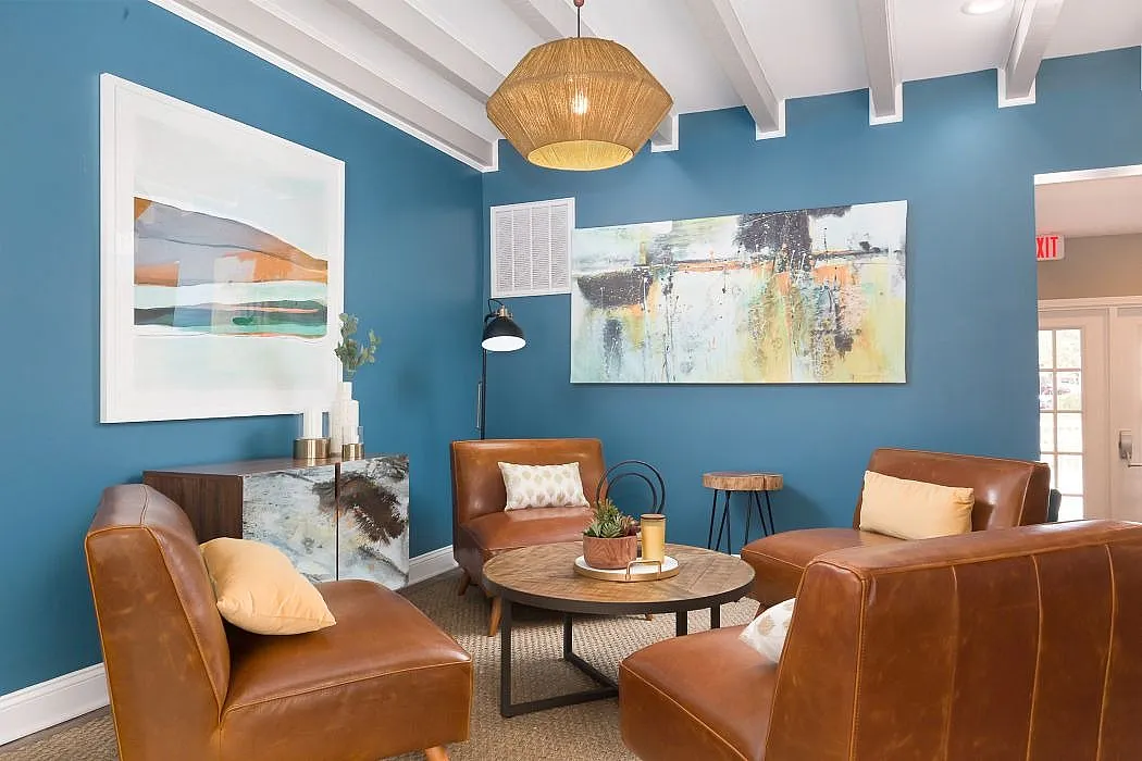 Bright and inviting lounge with rich brown leather chairs, vibrant blue accent wall, and modern abstract art.