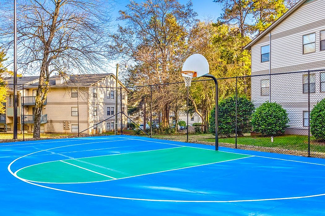 Vibrant outdoor basketball court surrounded by lush greenery and modern apartment buildings, perfect for active living.