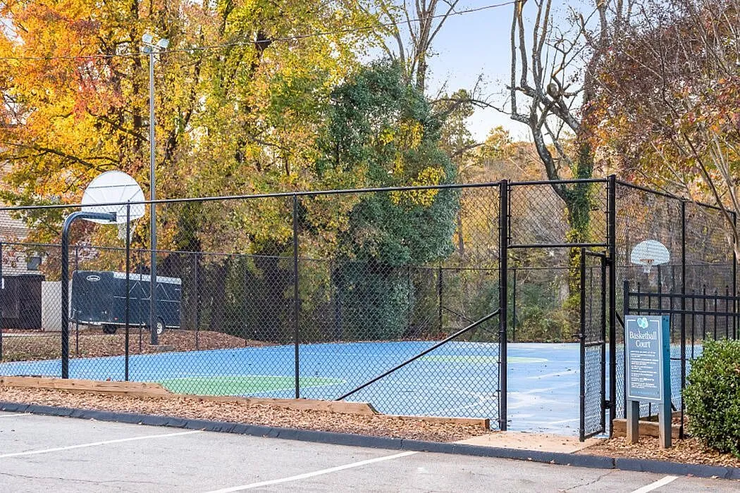 Charming outdoor basketball court surrounded by lush autumn trees, perfect for active living and leisure.