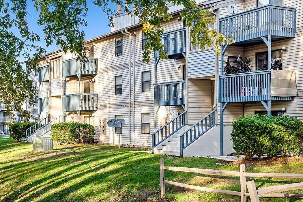 Charming apartment exterior with private balconies, nestled in lush greenery and offering serene living in a well-maintained community.