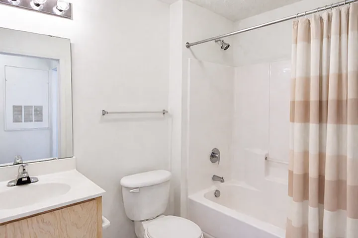 Bright and modern bathroom featuring a sleek vanity, large mirror, and chic shower curtain.