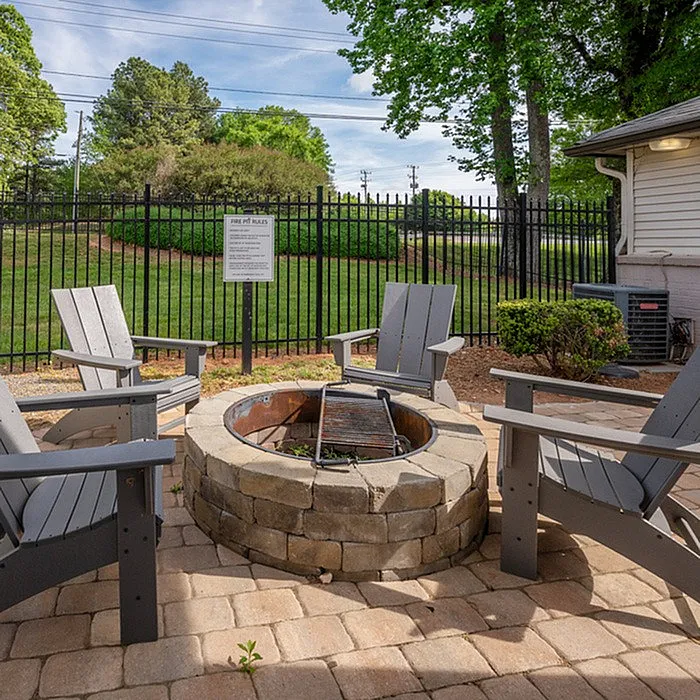 Inviting outdoor patio featuring a cozy fire pit surrounded by Adirondack chairs, perfect for social gatherings.