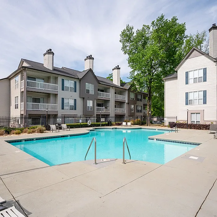 Charming apartment complex with a refreshing swimming pool, surrounded by lush greenery and elegant multi-story buildings perfect for relaxation and socializing.
