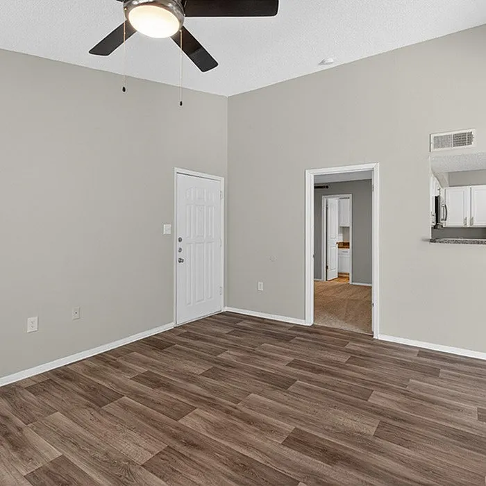 Bright and open living area with elegant wood flooring, ceiling fan, and convenient kitchen pass-through.