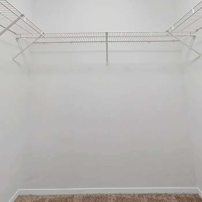 Spacious walk-in closet with clean white walls and ample shelf space, perfect for organizing your wardrobe.