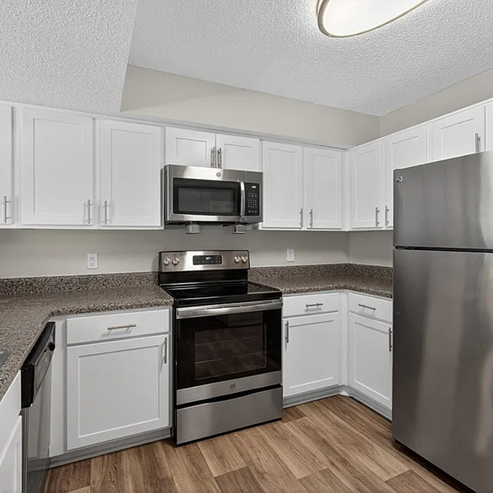 Modern kitchen with sleek stainless steel appliances, bright white cabinets, and elegant granite countertops.