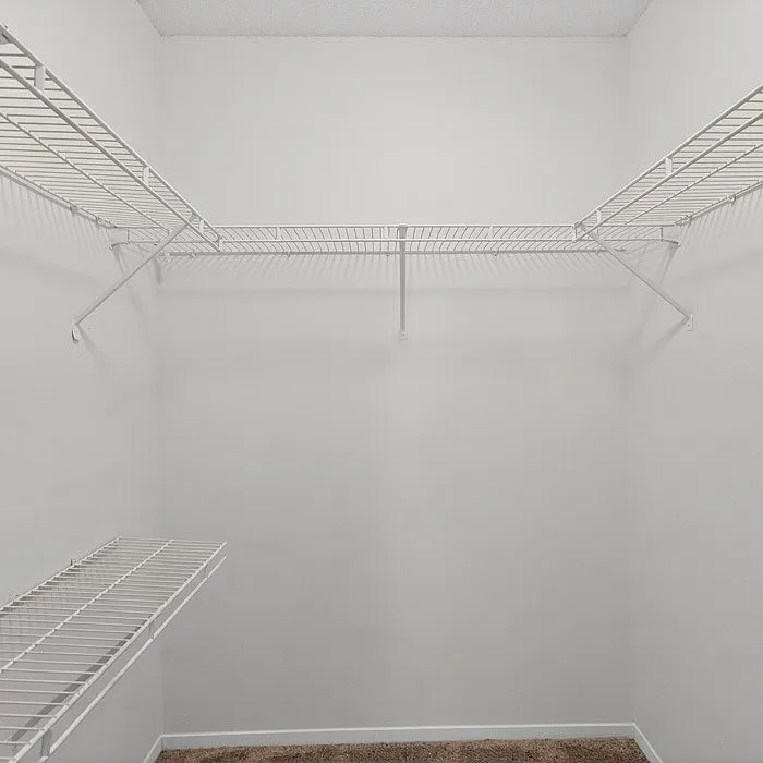 Spacious walk-in closet with sleek white wire shelving, perfect for organized storage solutions.
