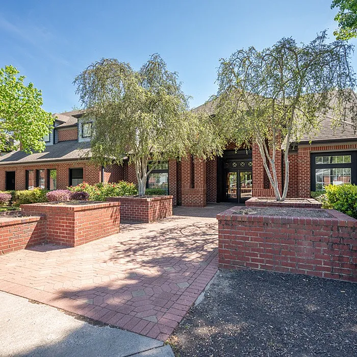 Charming brick exterior of a residential building with lush greenery and welcoming pathway.