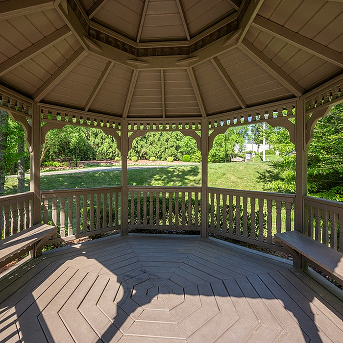 Charming wooden gazebo with inviting benches, nestled in a lush garden setting, perfect for relaxation and outdoor enjoyment.