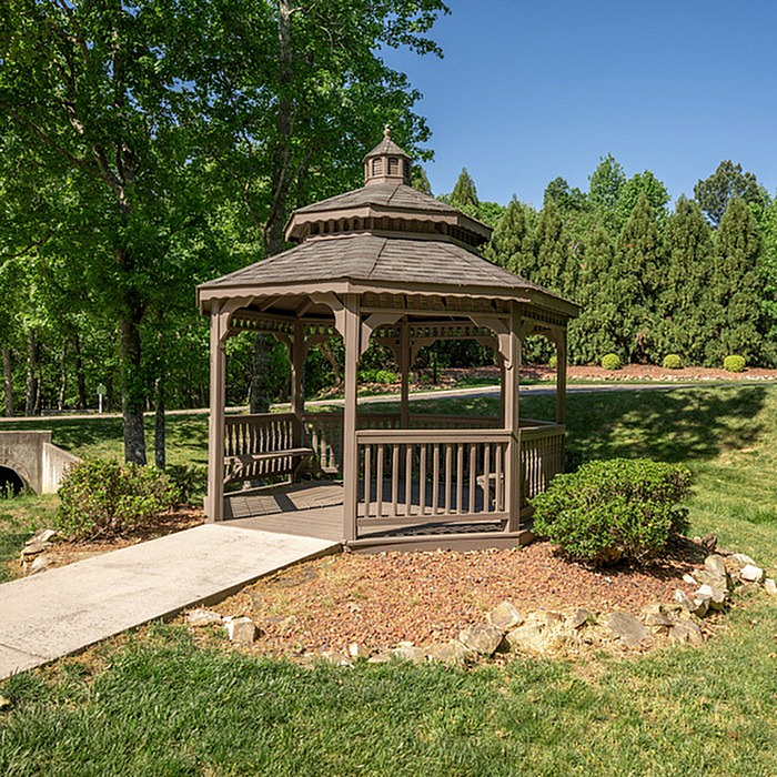Charming wooden gazebo nestled in a lush, green park setting, perfect for relaxation and outdoor gatherings.