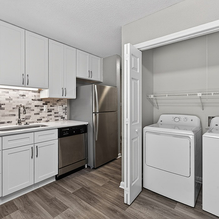 Modern kitchen with sleek stainless steel appliances, elegant white cabinetry, and adjacent laundry area for convenience.