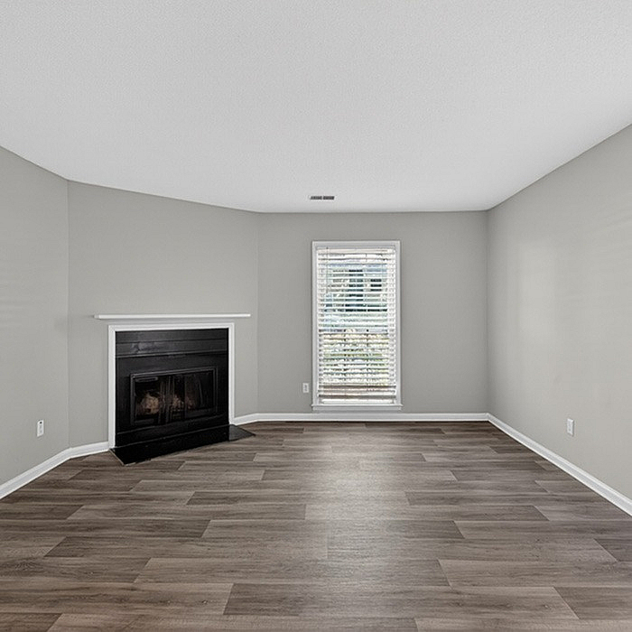 Bright, modern living room with elegant hardwood floors and a cozy fireplace, filled with natural light from a large window.