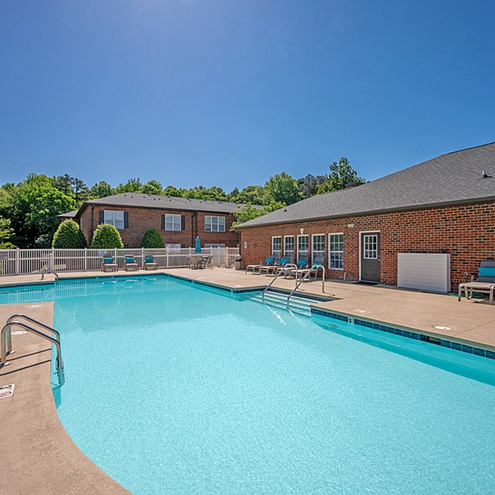 Inviting outdoor swimming pool with sun loungers and brick buildings in a serene residential setting.