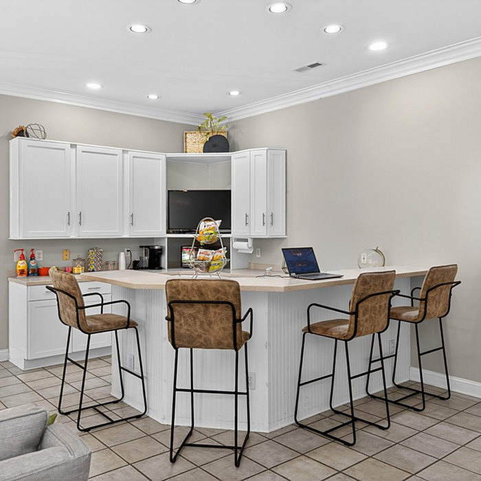 Modern kitchen with elegant bar seating, sleek white cabinets, and ambient lighting for a warm and inviting atmosphere.