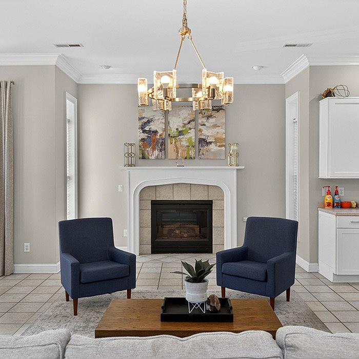 Elegant living room with cozy fireplace, modern chandelier, and stylish navy armchairs, creating a warm and inviting atmosphere.