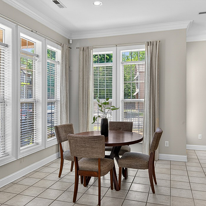 Bright dining area with natural light streaming through large windows onto a cozy table for four, perfect for intimate gatherings.