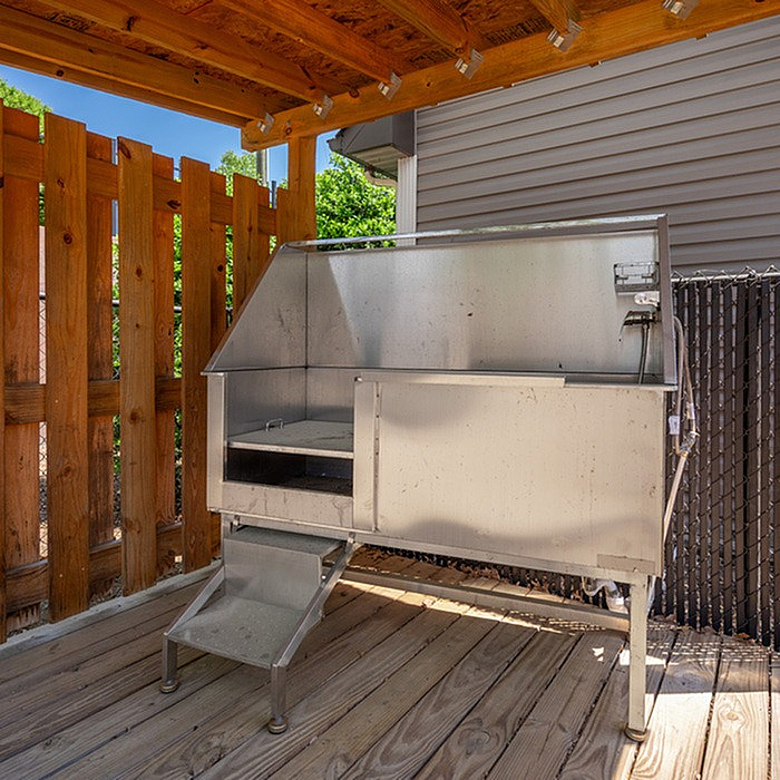 Charming wooden porch showcasing a modern outdoor cat shelter with durable metal structure, perfect for pet safety and comfort.