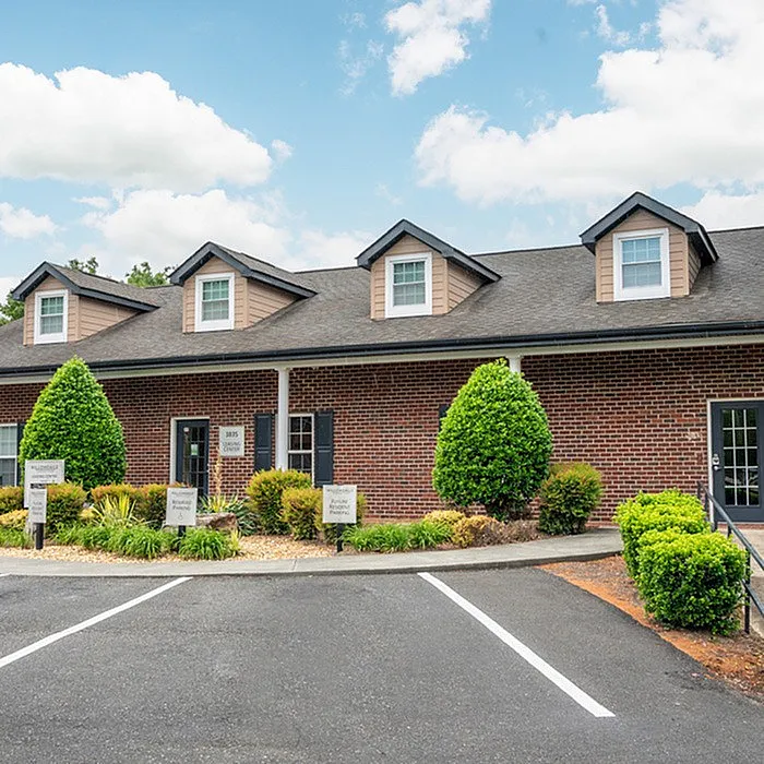 Charming brick-front apartment building with manicured landscaping and inviting entrance, ideal for stylish living.
