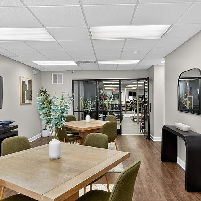 Elegant common area with stylish tables, inviting seating, and modern decor, adjacent to a state-of-the-art fitness center.