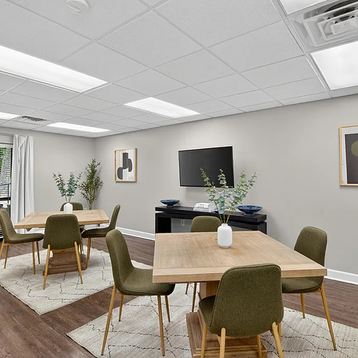 Modern communal dining area with stylish tables, chic green chairs, and decorative plants, perfect for gatherings and relaxing moments.