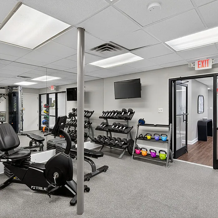 Modern fitness center with a range of equipment including cardio machines, dumbbells, and colorful kettlebells under bright lighting.