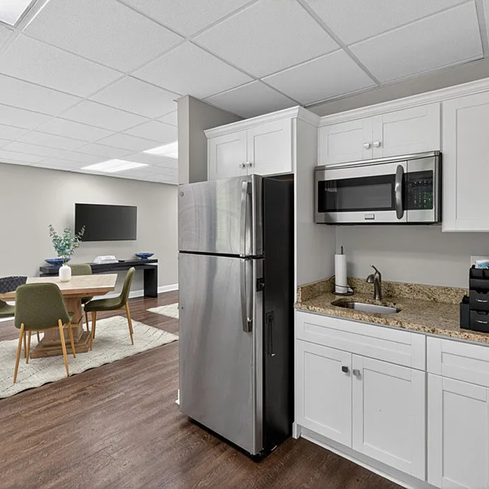Modern kitchen with granite countertops, stainless steel appliances, and adjacent dining area featuring stylish table and chairs.