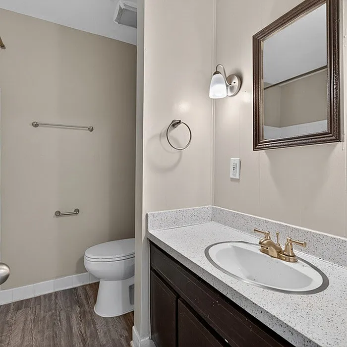 Elegant bathroom featuring modern vanity with sleek faucet and large mirror, complemented by soft, neutral walls and stylish lighting.